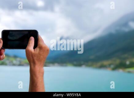 Des Menschen Hand Handy und das Bild von der schönen Landschaft in Norwegen Fjorde. Kreuzfahrt Konzept. Stockfoto