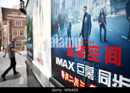 ---- Ein Fußgänger geht hinter einem Plakat des Films, Gründung, mit der Beschilderung von IMAX in einem Kino in Shanghai, China, 7. September 2010. Ein Jahr Stockfoto