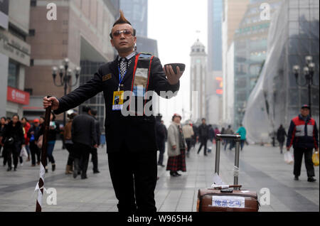 Zhou Fei, wie die Angesagtesten Bettler in China bekannt ist, stellt in einer Fußgängerzone in Chongqing, China, 23. Februar 2012. Anzug, gespritzt Stockfoto