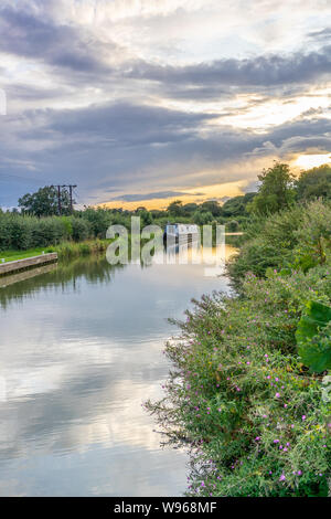 Ein Kanalboot / Schmalboot vor Anker entlang der Kennet und Avon Canal bei Sonnenuntergang im Sommer, Wiltshire, England, Großbritannien Stockfoto