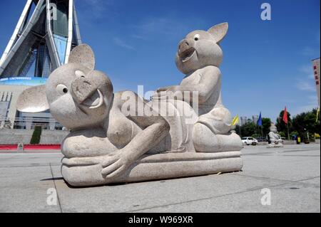 Eine steinerne Skulptur von zwei Schweine, die wie Paarung zu schauen auf dem Platz vor dem Wahrzeichen Bau angezeigt ist, die Zentrale Ebene Blessednes Stockfoto