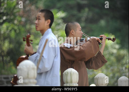 Ein chinesischer Buddhistischer Mönch und Nonne von Guangxuan Kunst Truppe Praxis spielen Violine während einer Schulung bei Tiantai Tempel auf Berg Tiantai in H Stockfoto