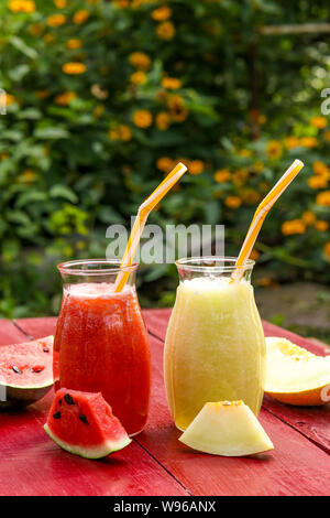 Hausgemachte nützliche Frucht Smoothies aus Wassermelone, Melone auf einem Tisch im Garten, vertikale Ausrichtung Stockfoto