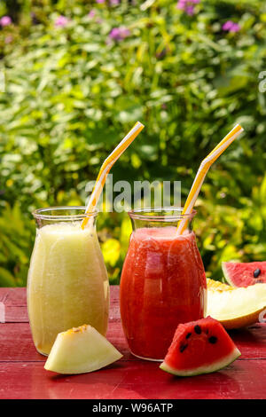 Hausgemachte nützliche Frucht Smoothies aus Wassermelone, Melone auf einem Tisch im Garten, vertikale Ausrichtung Stockfoto