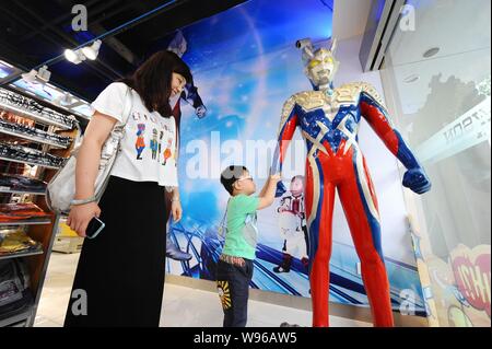 Kunden werden von einem ultraman Modell zu einem ultraman-themed Convenience Store von Lawson in Shanghai, China, 8. Juni 2012 gesehen. Eine Ultraman-themed Co Stockfoto