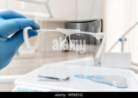 Close-up Hand der Zahnarzt in den Handschuh hält zahnmedizinische Schutzmaske. Büro, wo Zahnarzt Inspektion durchführt und abschließt. Stockfoto