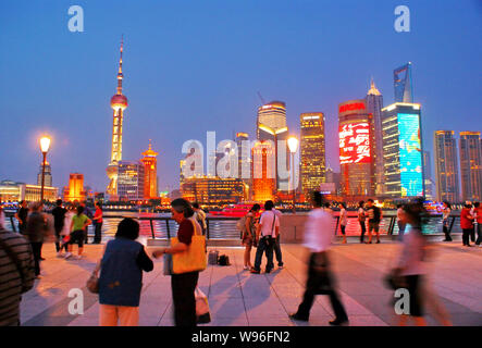 ---- Touristen besuchen die Promenade am Bund entlang des Huangpu Fluss gegen den nächtlichen Blick auf Pudongs Finanzdistrikt Lujiazui mit dem Orient Stockfoto