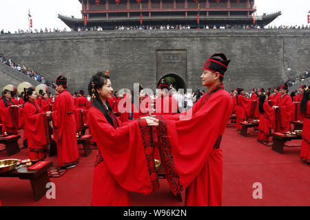 Paare der Jungvermählten im traditionellen Han Kostümen halten Hände als Teil der alten Chinesischen nuptial rites während einer Gruppe Trauung in XiAn c Stockfoto