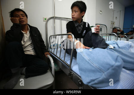 Chinesischer junge Xiao Männer, die seine große Füße mit Tuch sieht seinen Vater am Krankenhaus der Kinder von Shanghai in Shanghai, China, 21. November gewickelt Stockfoto