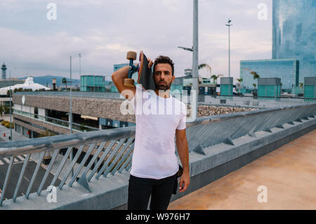 Skateboarder steht mit Skateboard in der modernen Stadt Terrasse Stockfoto