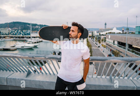 Skateboarder steht mit Skateboard in der modernen Stadt Terrasse Stockfoto