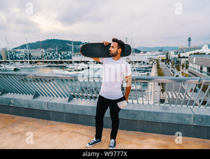 Skateboarder steht mit Skateboard in der modernen Stadt Terrasse Stockfoto