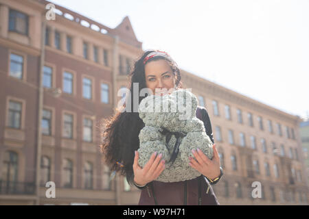 Hübsche Frau, die zu Fuß in die Stadt mit grauen Teddybär von foamirane Rosen. Stockfoto