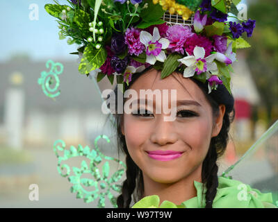 Kostümierte schöne Thai Mädchen mit Blumen im Haar nimmt Teil an der Geschichte des Dorfes Lanna street parade und Lächeln für die Kamera. Stockfoto