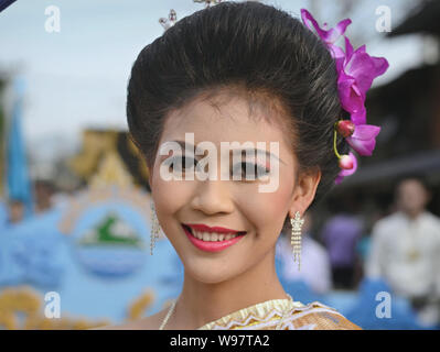 Gekleidet - sich hübsche Thai Mädchen mit Blumen im Haar nimmt Teil an der Geschichte des Dorfes Lanna street parade und Lächeln für die Kamera. Stockfoto