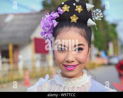 Kostümierte schöne Thai Mädchen mit Blumen im Haar nimmt Teil an der Geschichte des Dorfes Lanna street parade und Lächeln für die Kamera. Stockfoto