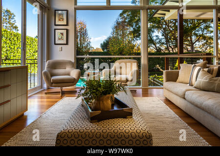 Lounge in der inländischen Haus mit Teppich und Stühle, mit Fenster zum Garten und Poolbereich Stockfoto