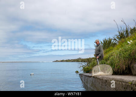 Hokitika, West Coast, Neuseeland, Oktober, 19 2017: Eine ältere whitebaiter Fische am Ufer des Flusses von Hokitika River auf der Flut Stockfoto