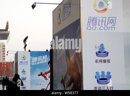 ------ Anwohner vorbei an Werbung für QQ.com von Tencent in Peking, China, 11. Dezember 2010. Tencent Holdings Ltd. in China gab eine 6 Stockfoto