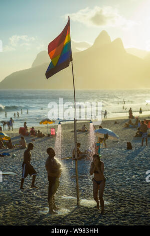 RIO DE JANEIRO - Februar, 2018: Beachgoers Dusche unter einem Gay Pride Regenbogen Flagge am Strand von Ipanema, eine Nachbarschaft für Vielfalt und Toleranz bekannt. Stockfoto