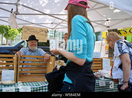 Farmers Market, Madison, WI USA. Aug 2018. Ein jolly Bäckerei Verkäufer lächelt und spricht auf eine Frau. Stockfoto