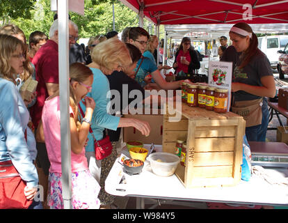 Farmers Market, Madison, WI USA. Aug 2018. Eine junge Frau im Hintergrund heraus versuchen, einige der Salsa Proben. Stockfoto