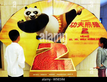 ---- Zwei chinesische Kinder zu einem Plakat des Films schauen, Kung Fu Panda 2, in einem Kino in Kunshan City, Central China Provinz Hubei, 31. Mai 2011. Po, Stockfoto