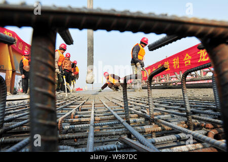 ------ Chinesische Arbeiter Zement die Oberfläche eines Teils der Qingdao Golf Brücke, auch als Die Qingdao Bay Bridge oder der Qingdao Haiwan Bridge bekannt, Stockfoto