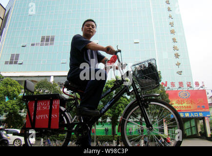 Eine lokale Radfahrer fährt mit dem Fahrrad auf einer Straße in Dongguan City, South China Guangdong Provinz, 9. März 2010. Stockfoto