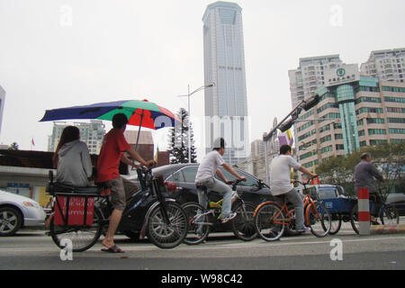 Lokale Radfahrer fahrt ihr Fahrrad auf einer Straße in Dongguan City, South China Guangdong Provinz, 9. März 2010. Stockfoto
