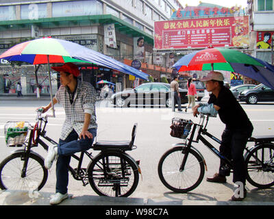 Lokale Bewohner sitzen auf ihren Fahrrädern auf einer Straße in Dongguan City, South China Guangdong Provinz, 9. März 2010. Stockfoto