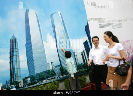 Lokale chinesische Bewohner vorbei an eine Werbung für die Shanghai International Finance Centre in der Lujiazui Finanzviertel in Pudong, Shangha Stockfoto