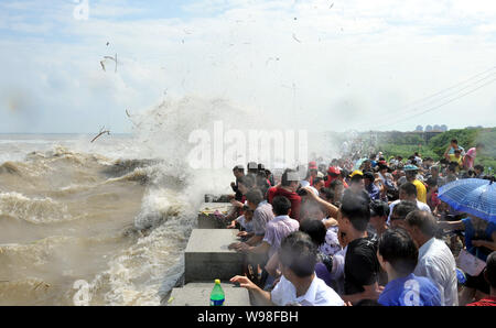 Besucher und Anwohner wie Wellen aus einem Gezeiten laufen Bohrung Schwankung hinter einer Barriere am Ufer des Qiantang Fluss in Haining City, East China Zhejiang Stockfoto