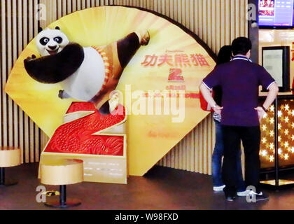 ---- Chinese Kinogänger, die neben einem Plakat des Films stehen, Kung Fu Panda 2, in einem Kino in Shanghai, China, 24. Mai 2011. Po, der Panda Witz Stockfoto