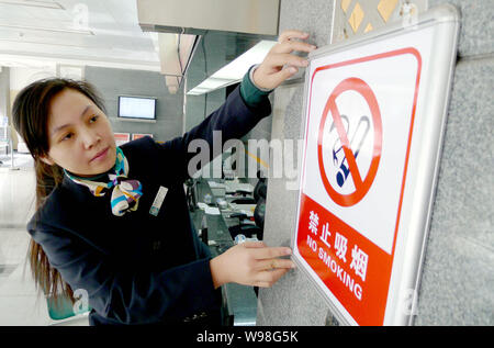 Ein chinesischer Mitarbeiter hängt ein Schild Rauchverbot an der Wand in einem Geschäft Hall des State Grid Corporation von China in Stadt Huaibei, East China Anhui provi Stockfoto