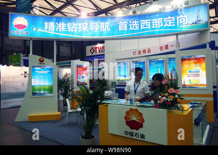 ------ Chinesische Mitarbeiter sind am Stand der CNPC (China National Petroleum Corporation), Muttergesellschaft von PetroChina gesehen, während einer Messe in Shangha Stockfoto