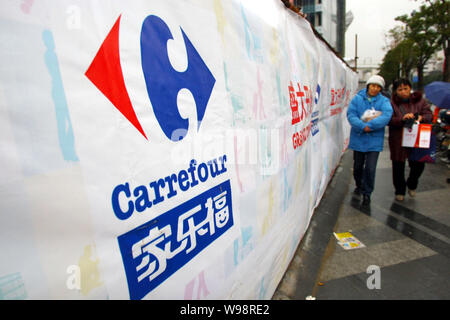 ------ Lokale chinesische Bewohner vorbei an einer Werbung für Carrefour in Shanghai, China, 17. Februar 2011. Frankreich-basierte supermarktkette Carref Stockfoto