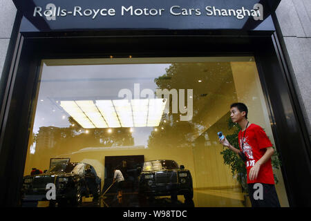 ---- Ein junger chinesischer Mann steht außerhalb der Rolls-Royce Showroom in Xintiandi in Shanghai, China, 27. Juli 2010. Sobald Rolls Royce boss Torst Stockfoto