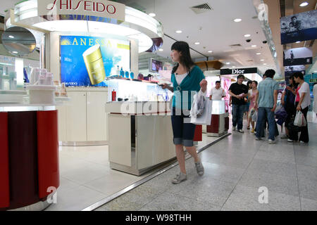 ---- Eine junge chinesische Frau geht hinter dem Stand von Shiseido an einem Abteilung Speicher in Shanghai, China, 10. Juni 2008. Mit dem Ziel, auf einer Burg zu Cash Stockfoto
