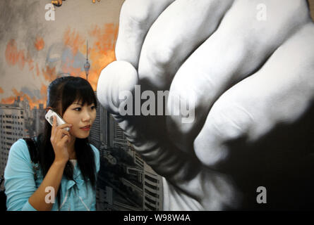 ---- Eine junge chinesische Frau sprechen über Ihr Mobiltelefon an ein Plakat mit einer Faust in Peking, China, 7. September 2008. Jeder Beijing Mobile Stockfoto