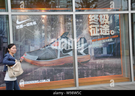 ---- Ein Fußgänger geht hinter einem Nike Store in Qingdao, China Provinz Shandong, 6. Oktober 2011. Nike Inc. will Verkauf von athletischen ap Ruck Stockfoto