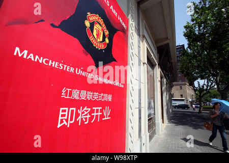 ---- Eine junge chinesische Frau geht hinter einem-bald-Öffnen der Manchester United Cafe Bar in Shanghai, China, 18. Mai 2011. Der amerikanische Besitzer von der Manche Stockfoto