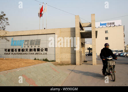 ---- Ein chinesischer Radfahrer fährt mit dem Elektrofahrrad aus der Fabrik von Knauf Gipskartonplatten (Tianjin) Co., Ltd. in Tianjin, China, 23. November 2010. Stockfoto