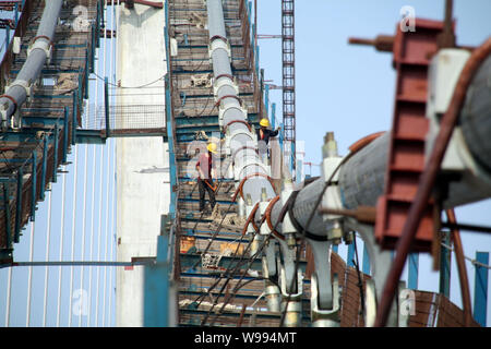 ------ Chinesische Arbeiter mount Tragseile an der Qingdao Golf Bridge, auch bekannt als der Qingdao Bay Bridge oder der Qingdao Haiwan Brücke, die in der Qing Stockfoto