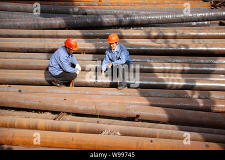 ------ Chinesische Arbeiter prüfen nahtlose Rohre aus Stahl in einem Stahlwerk in Stadt Huaibei, East China Provinz Anhui, 19. November 2010. In den USA Stockfoto