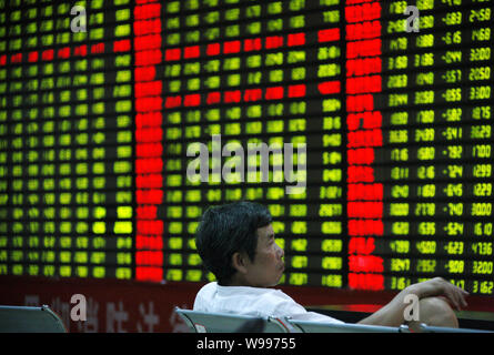 Ein Chinesischer Investor schaut bei Aktienkursen (rot für Preis steigt und grün für den Preis fallen) auf einer Börse brokerage House in Stadt Huaibei, East China ein Stockfoto