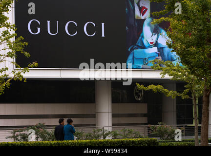 ---- Fußgänger vorbei an einer Anschlagtafel von Gucci in Peking, China, 4. Oktober 2011. Nach Berichten in den chinesischen Medien, Gucci China hat Biene Stockfoto
