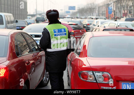 ---- Ein chinesischer Polizeioffizier leitet Datenverkehr inmitten einer Menge von Autos auf einer Straße in Peking, China, 3. Januar 2011. Beijing am Freitag (1. April 2011) Stockfoto
