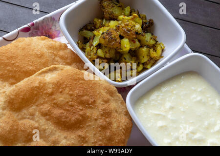 Puri Bhaji, Masala Aloo Sabzi Braten mit gebratenen Puri oder indisches Brot und Quark serviert. Stockfoto