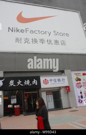 ---- Ein Fußgänger geht hinter einem Nike Store in Jiangbei, Central China Chongqing, 26. Februar 2010. Nike Inc. will Verkauf von athletischen appa Ruck Stockfoto